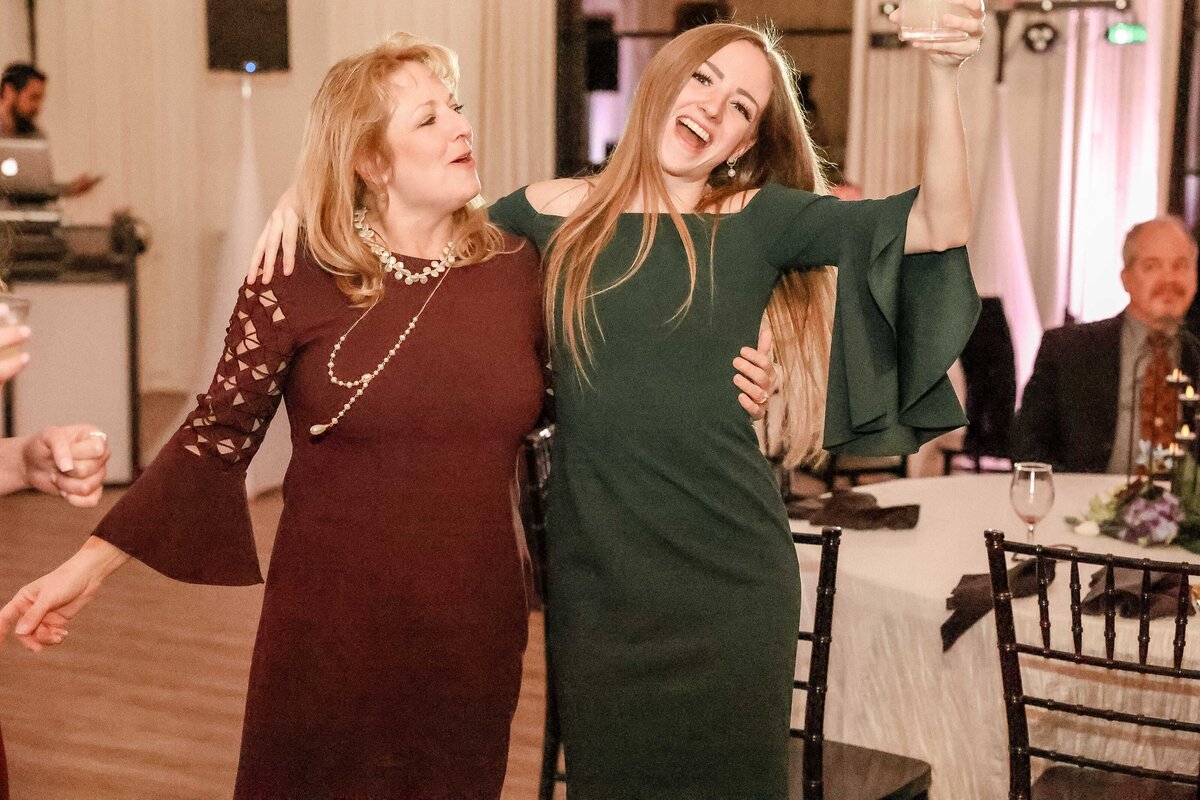 woman in maroon and woman in green dresses dance at Fort Worth wedding reception