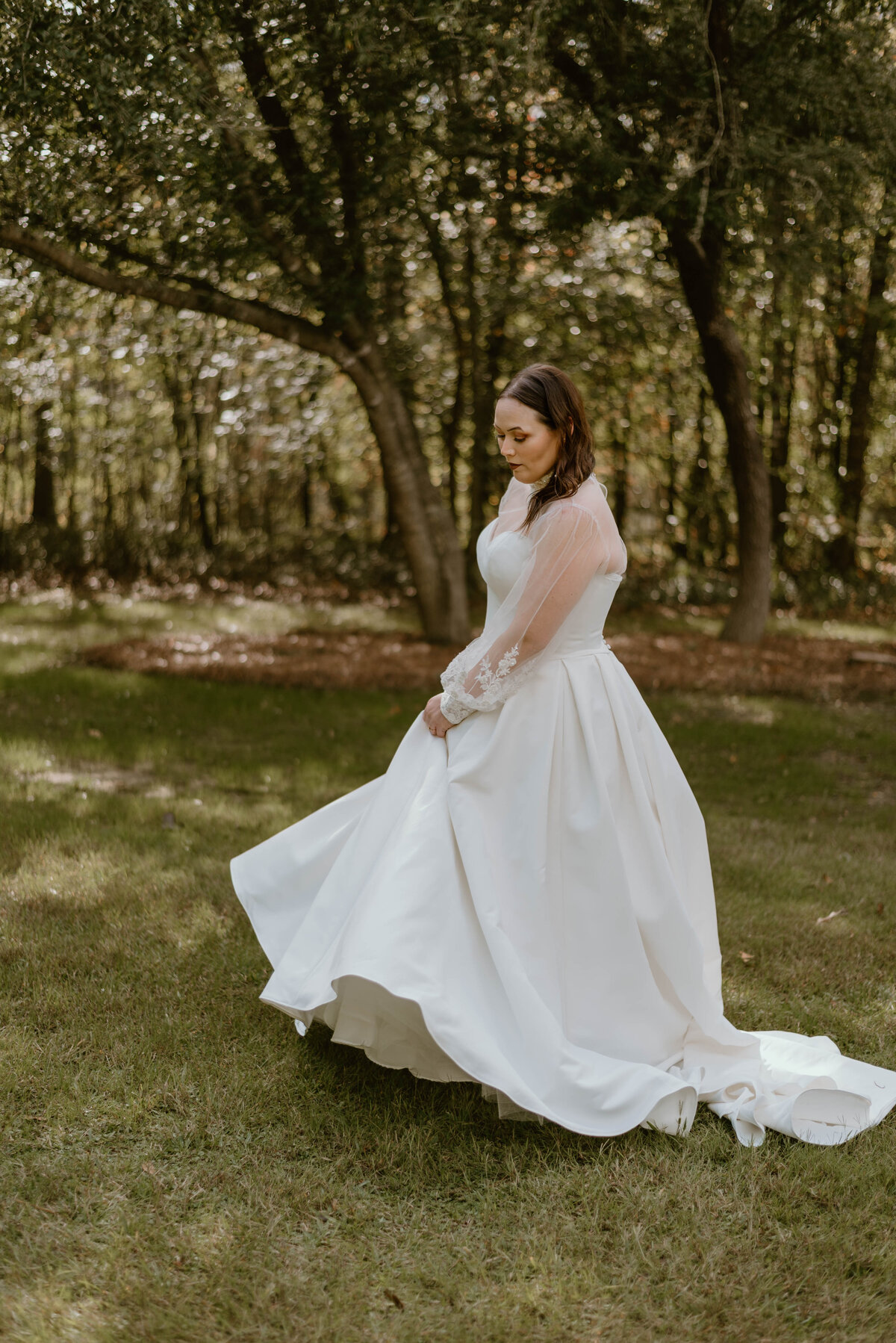 a bride twirling around in her wedding dress in a grassy field. 