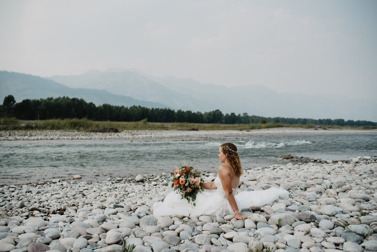 Jackson Hole Photographers capture bride sitting on rocks during bridal portraits