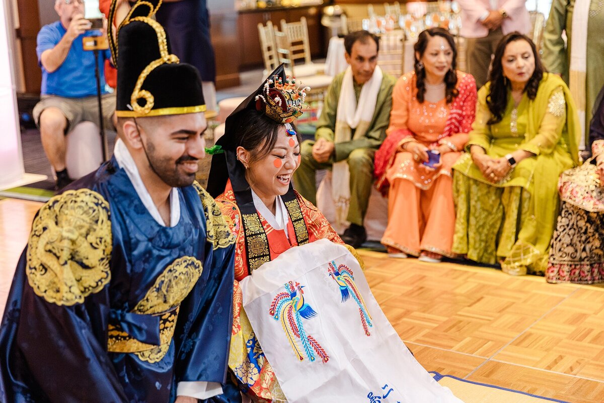 A traditional ceremony taking during on a couple's wedding day in DFW, Texas. The bride, groom, and family in the background all are dressed in traditional wedding garb.