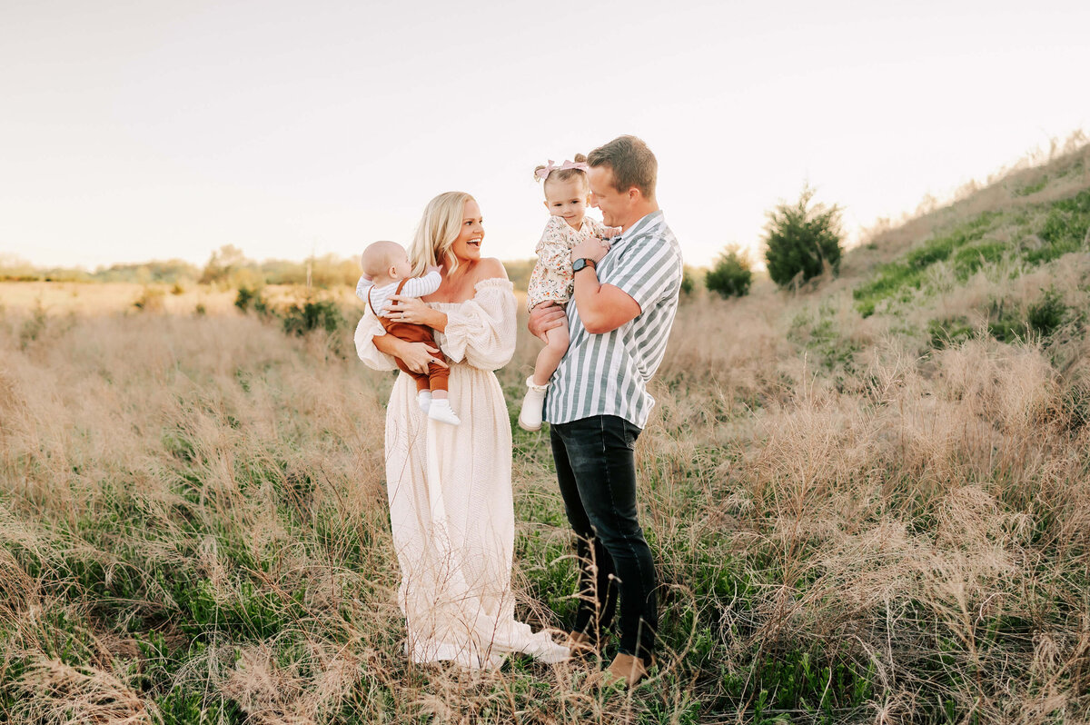 family smiling outdoors on hillside captured by Springfield MO family photographer Jessica Kennedy of The XO Photography