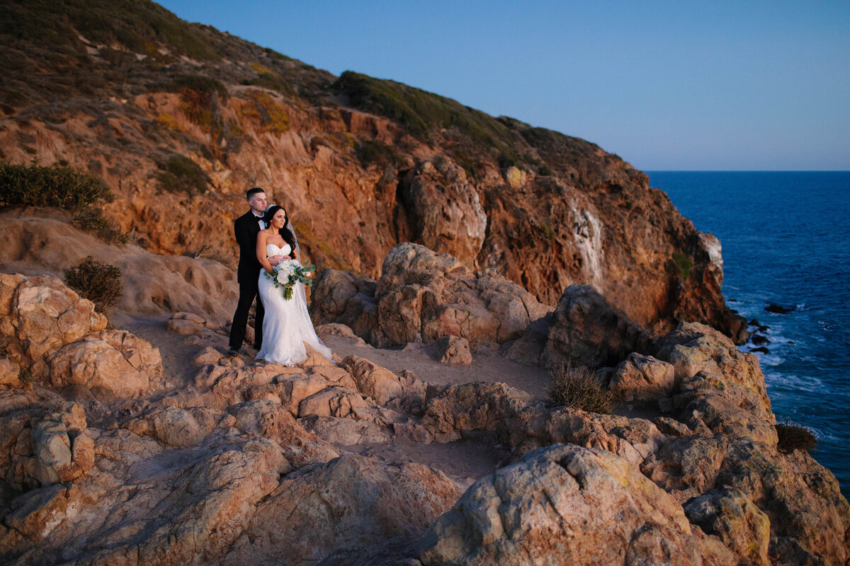 bride and groom on an ocean cliffside embracing