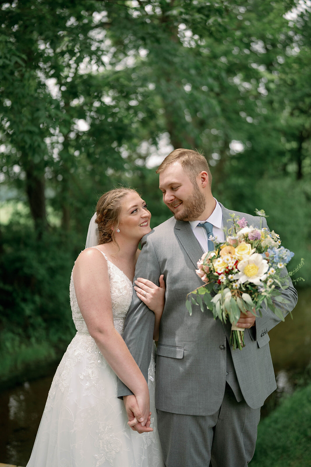 Romantic moment of the bride resting her chin on the groom’s shoulder during portraits at The Blue Heron Barn.