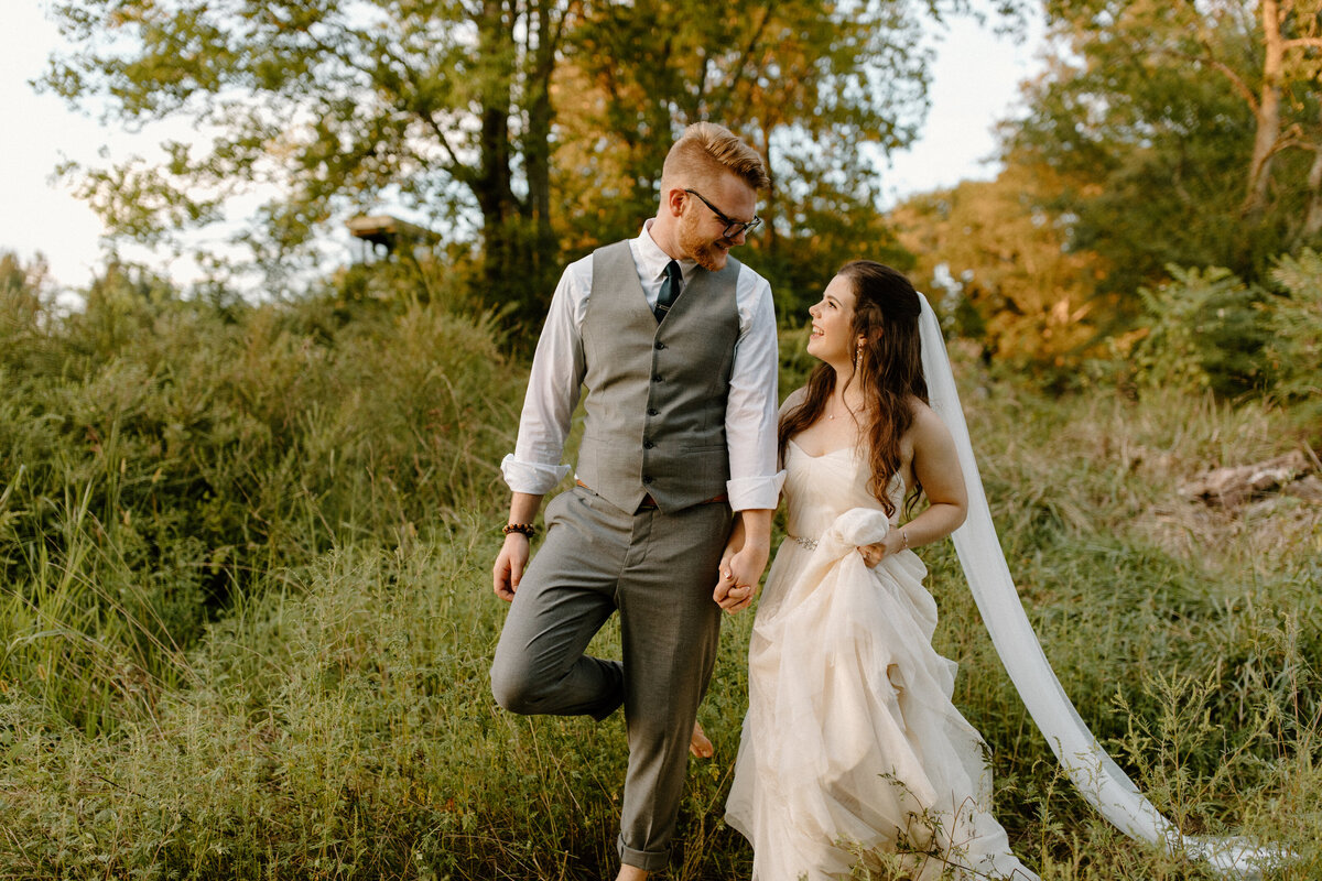 couple walking through tall grass holding hands at their lynchburg virginia wedding
