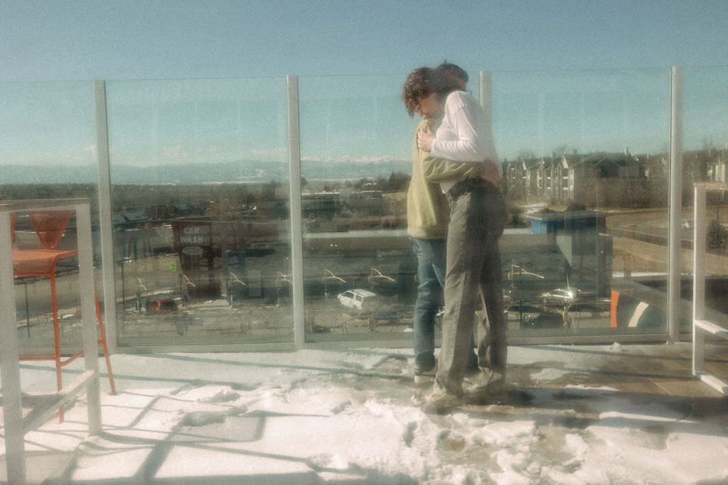 A couple hugging on a rooftop deck.