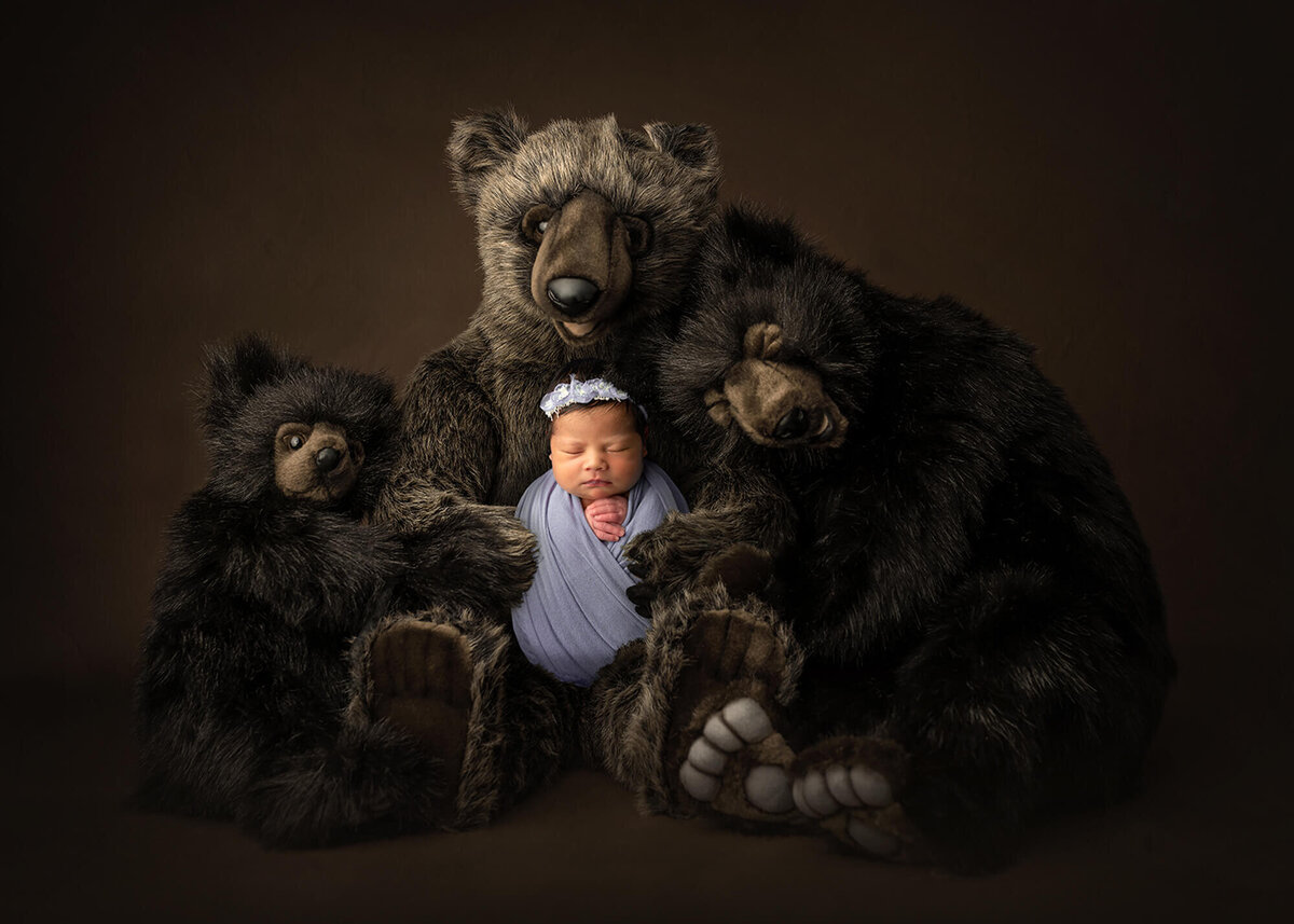newborn cuddling with teddy bears