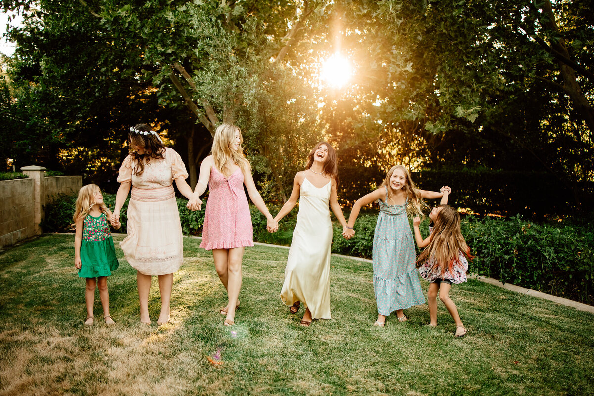 Backlit joyful image of 6 girl cousins swinging their arms and laughing