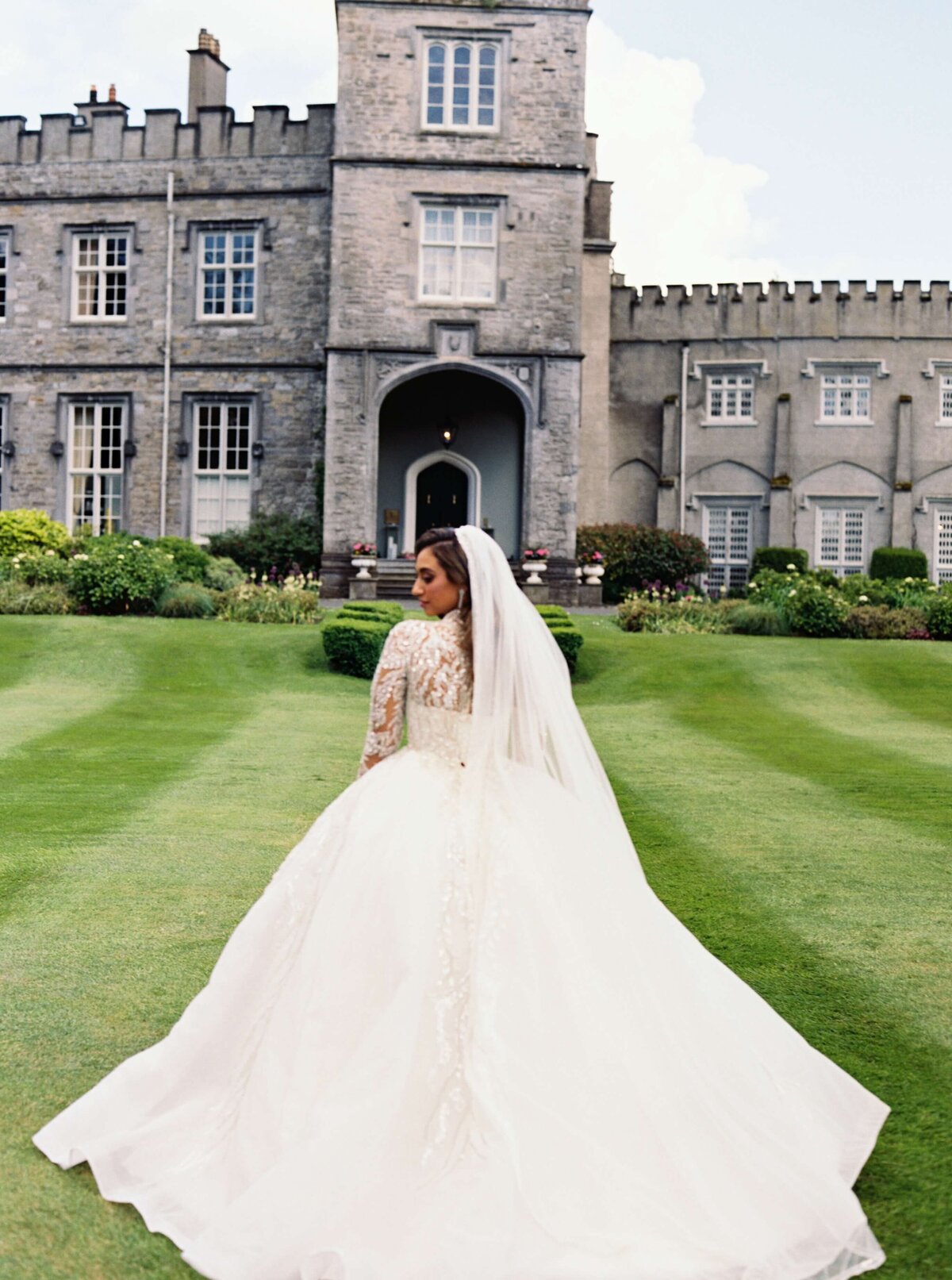 A wedding photo of a bride in a long white flowing dress on the gardens at Luttrellstown Castle