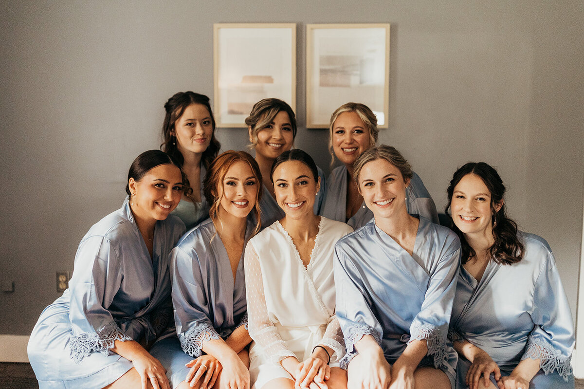 a bride with her bridesmaids wearing matching blue silk robes in the preparation suite at Willowbrook Wedding venue near Pittsburgh