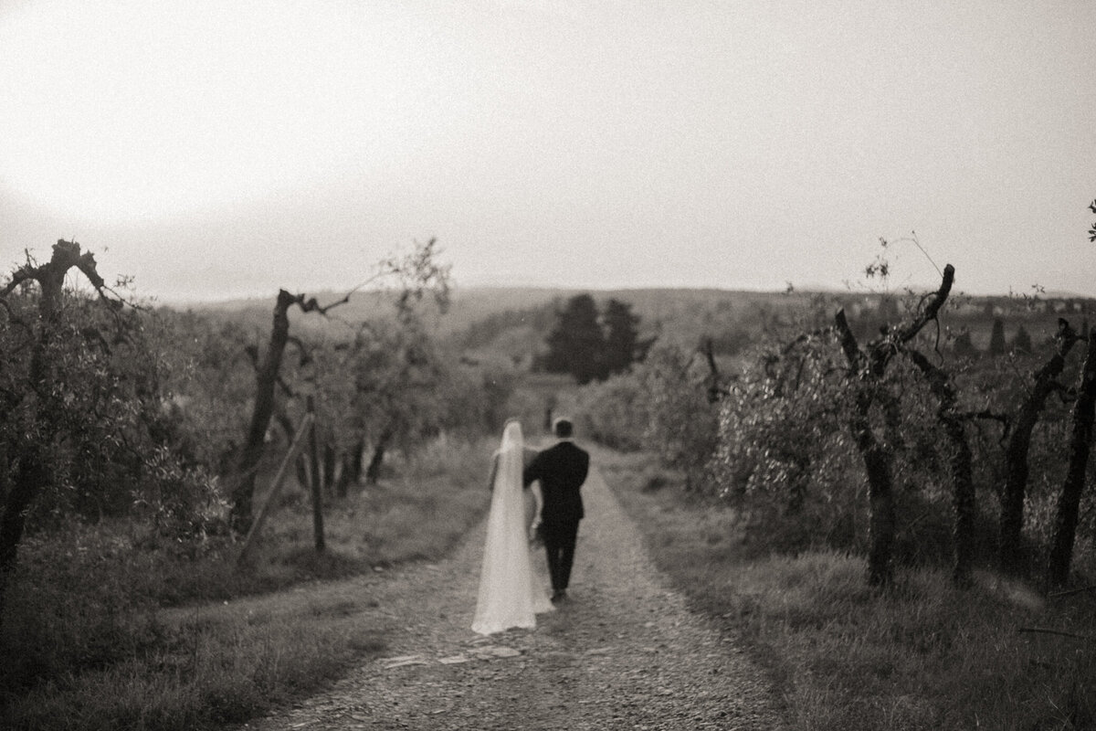 Bride and groom walk into the distance at Castello il Palagio wedding