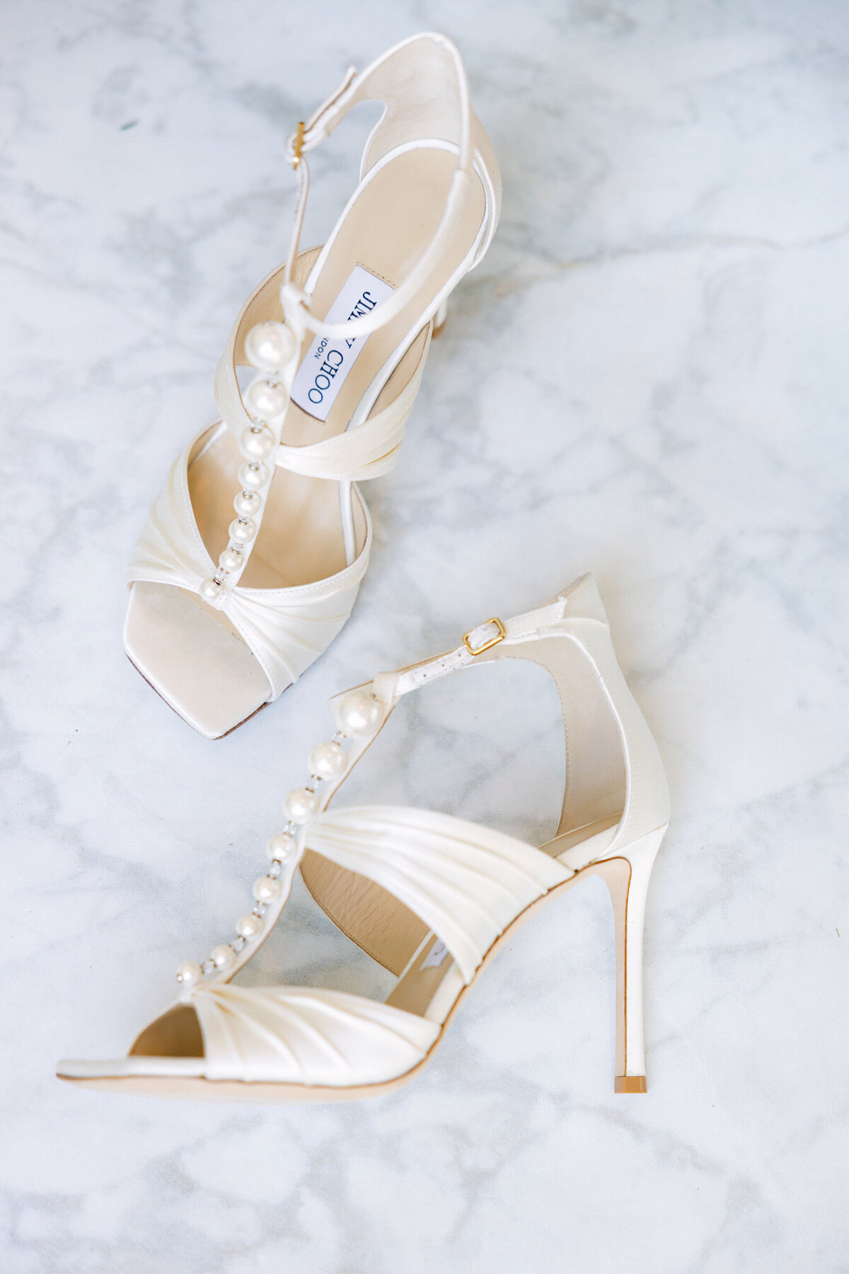 close up of Jimmy Choo bridal shoes adorned with pearls at The Adolphus in Dallas, showcasing elegant footwear for a luxury wedding.