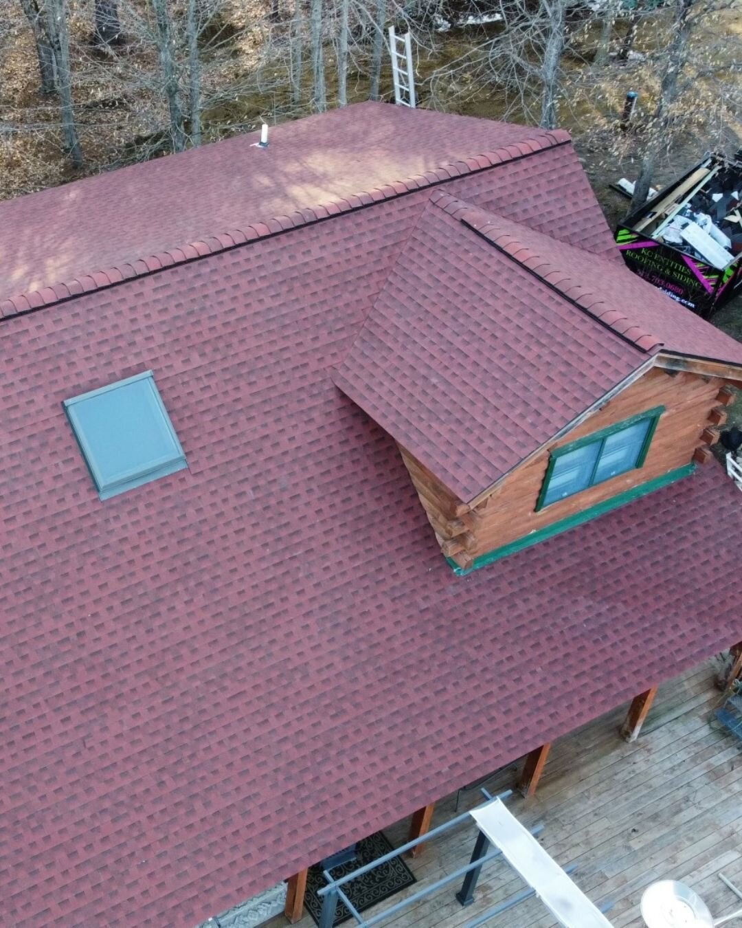 Cabin with red asphalt shingles from a roof replacement