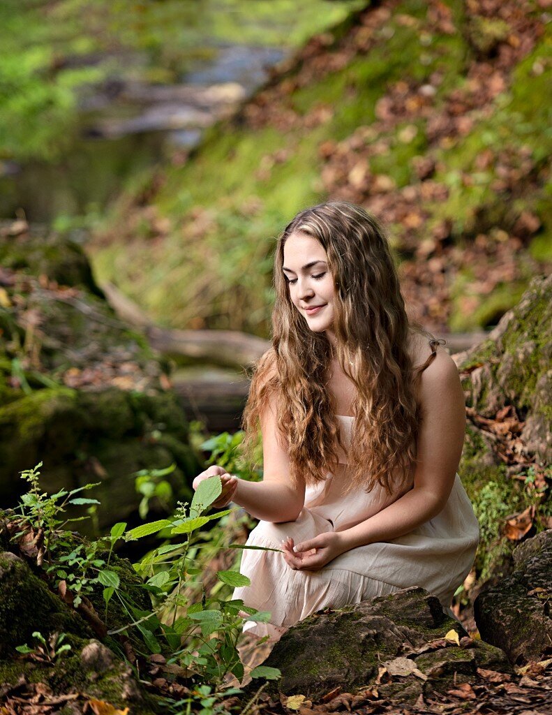 senior girl kneeling in woods