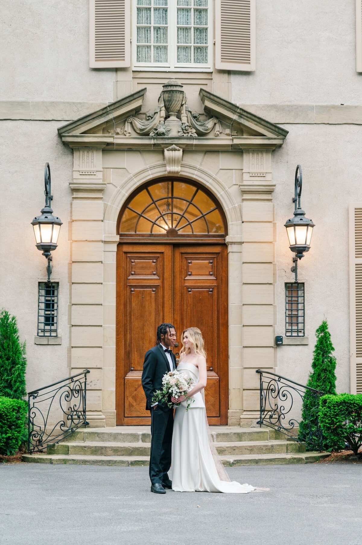 A bride and groom smiling closely at one another outside of Glen Manor House. 