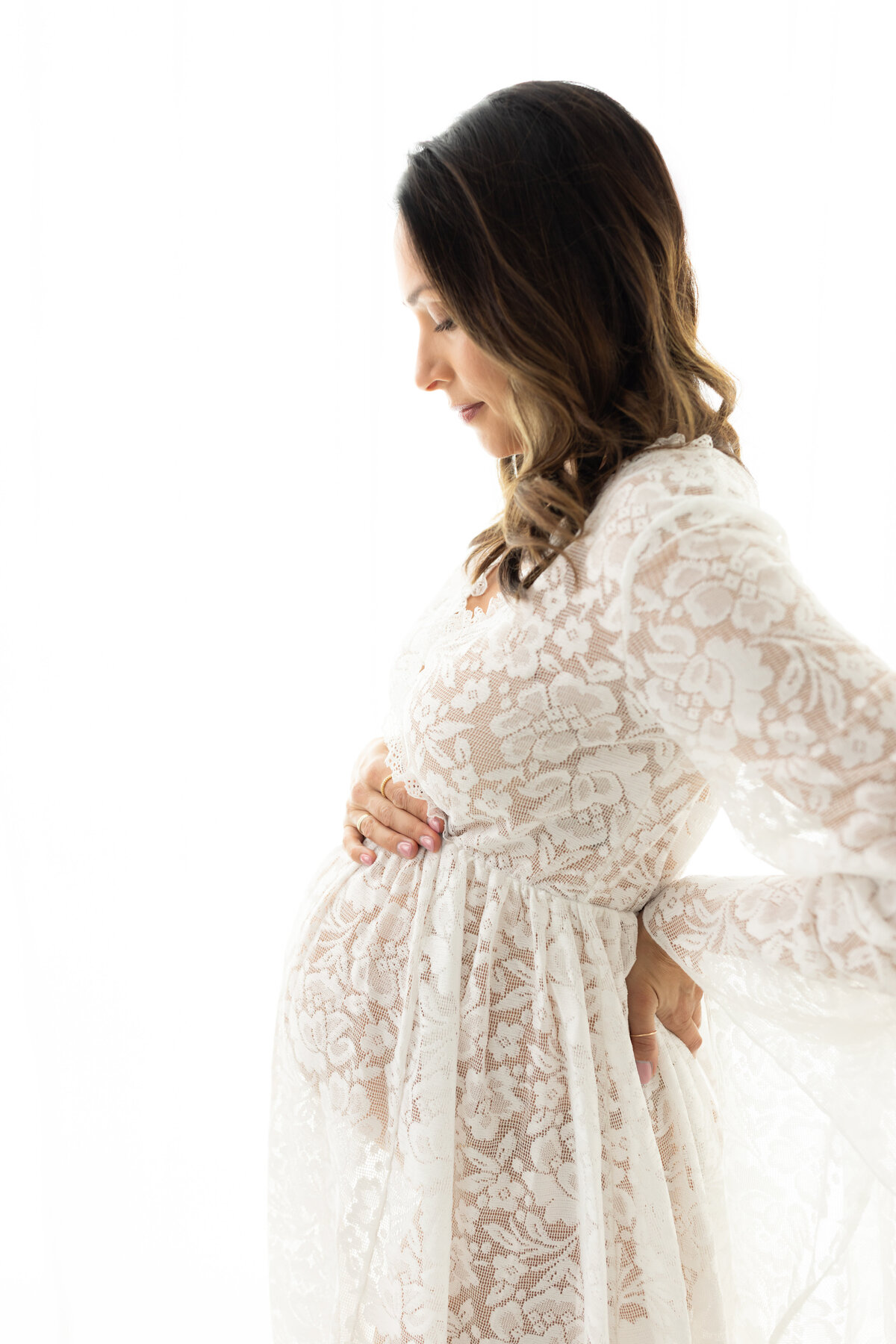 pregnant mother in white lace maternity gown holding baby bump for maternity photoshoot cleveland maternity photographer