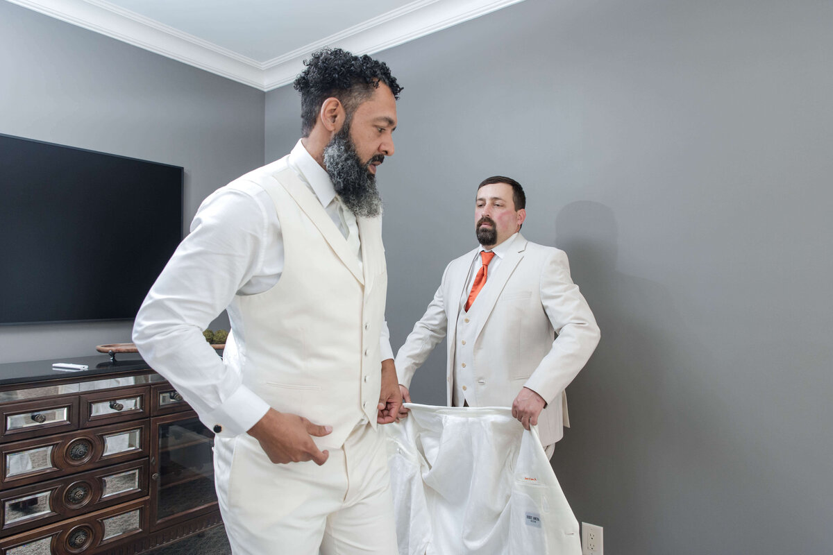 A stylish groom prepares for his big day, adjusting his elegant white suit.