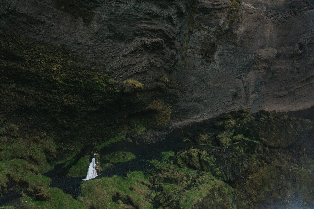 The couple, hand-in-hand, explores the peaceful surroundings of a hidden waterfall in Iceland 