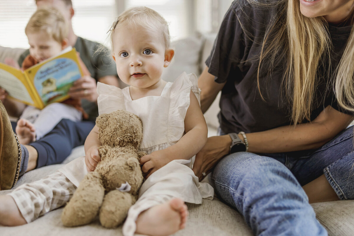 a toddler sits on the couch with her family in her home in little elm texas