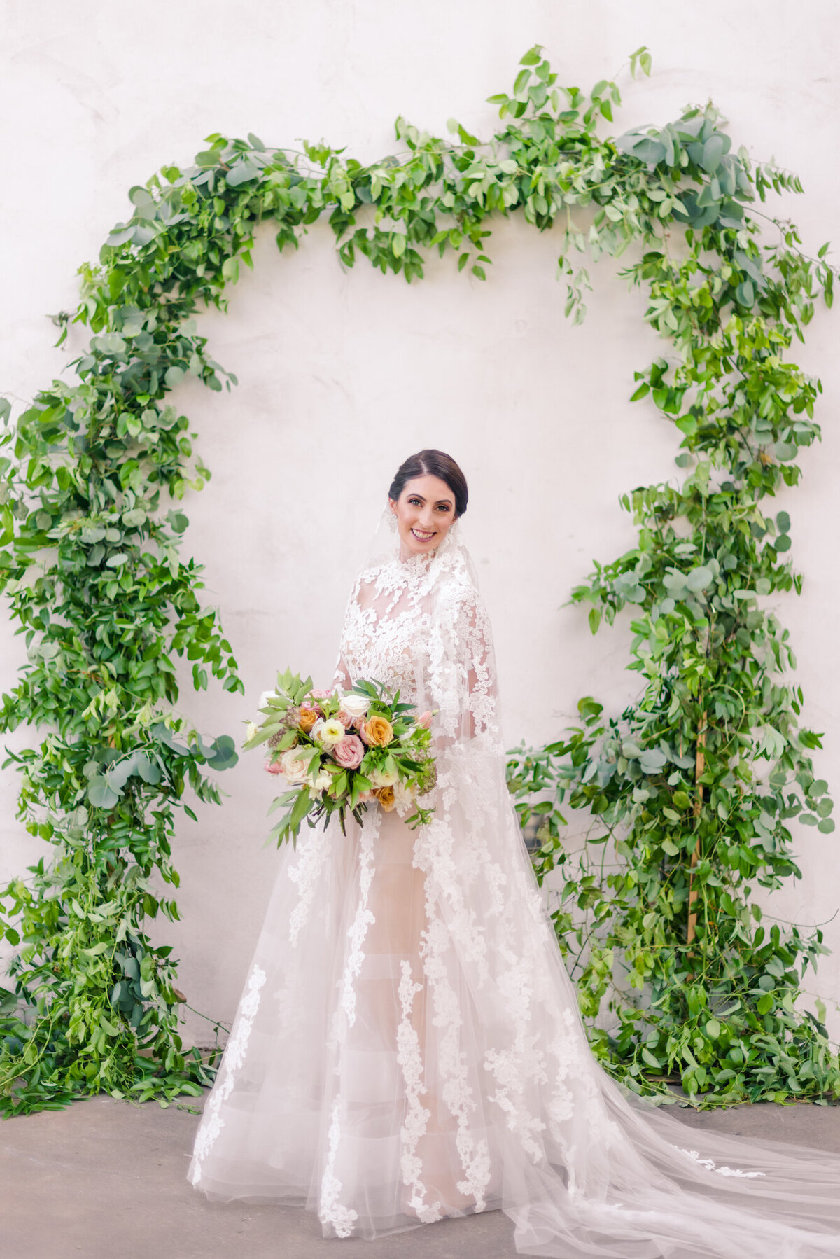 Bride under greenery arch
