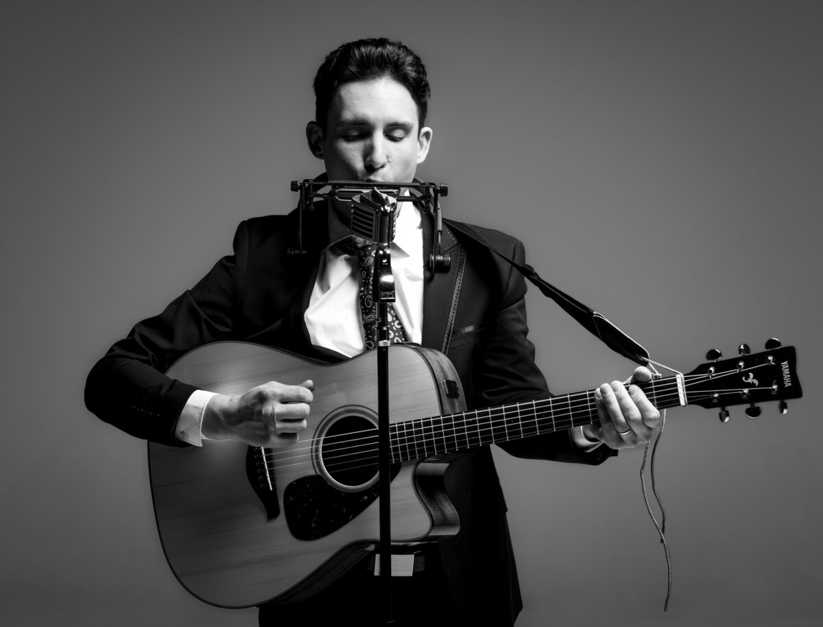 A musician playing guitar and harmonica at the same time.