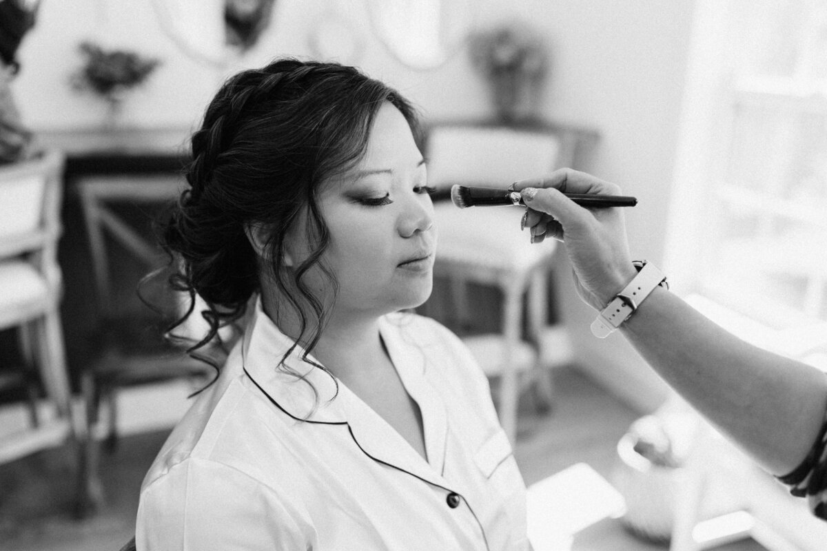 black and white photo of a bride getting makeup done