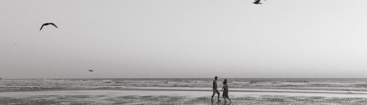 A playful engagement session on the beaches of the Oregon coast. Couple is running through the ocean while birds fly overhead.