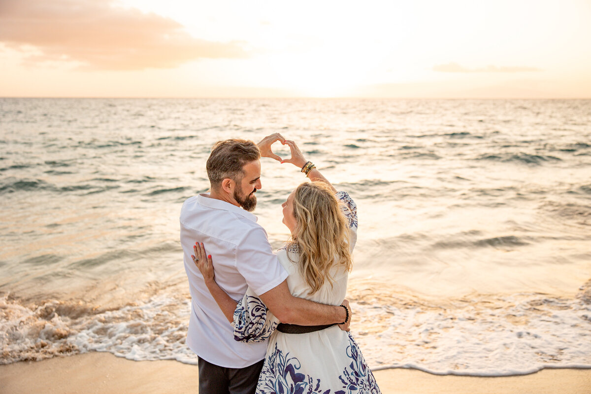 Maui Family Photographers capture couple creating heart with hands during beach photos