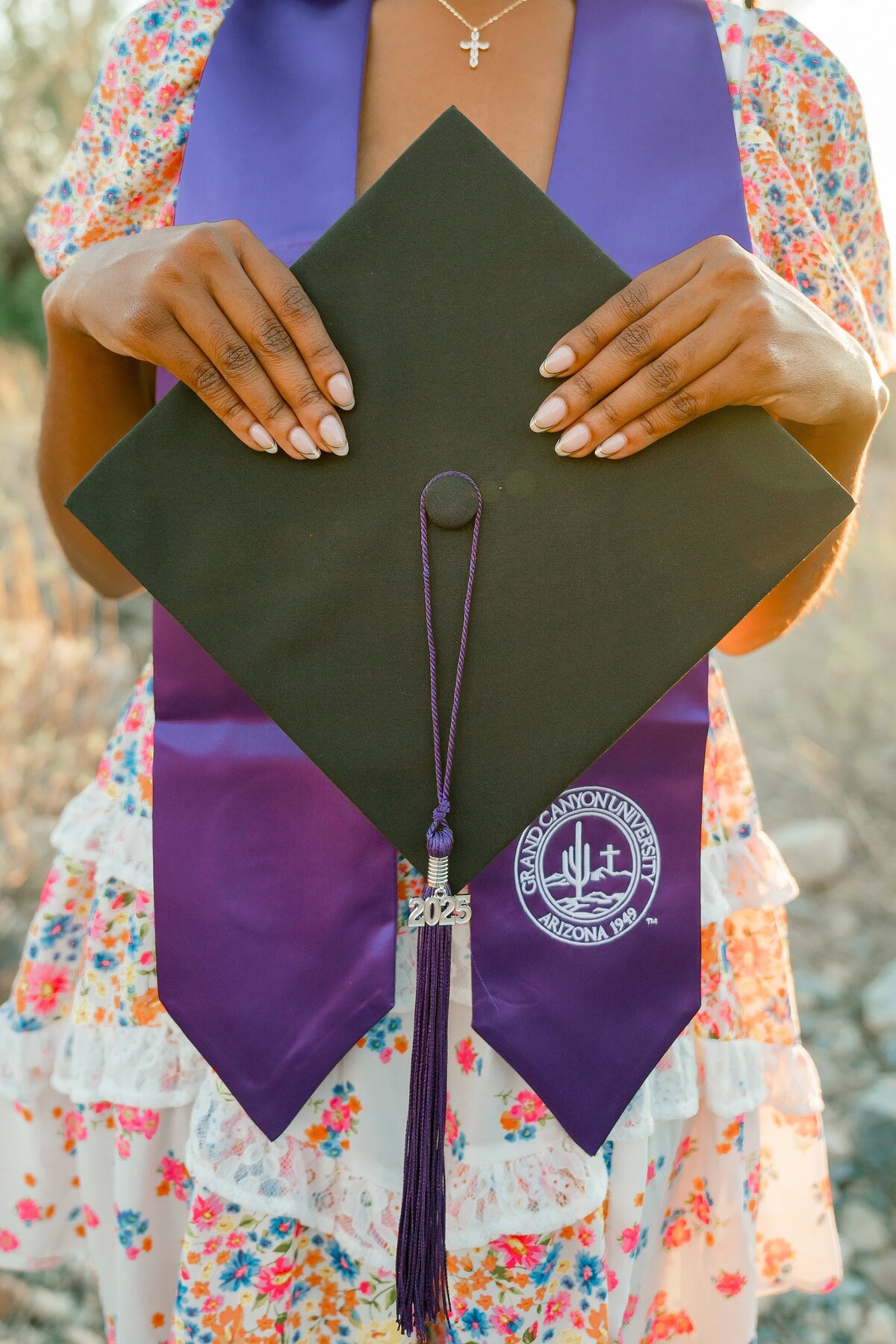 senior girl holding up cap in the arizona desert graduating from GCU
