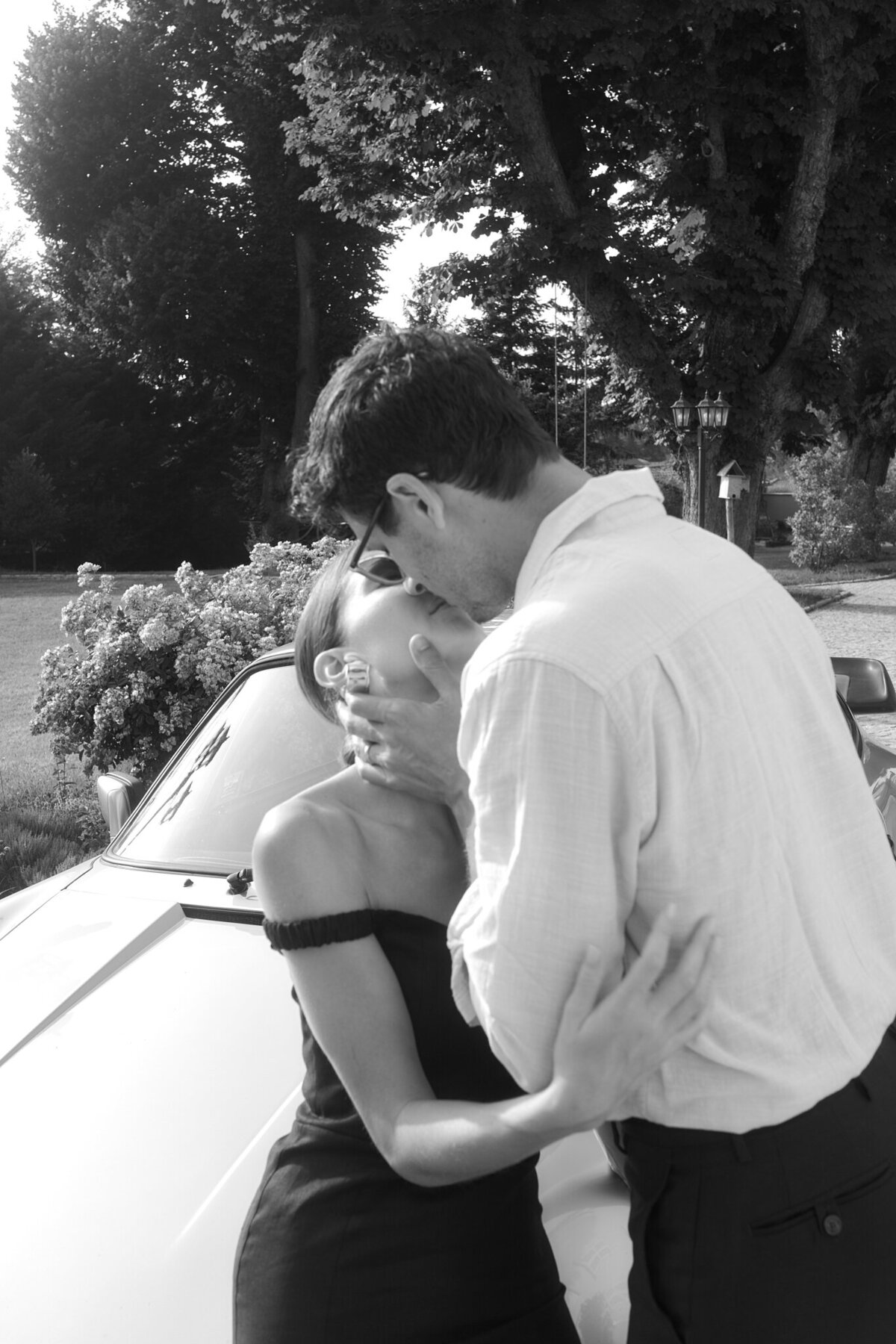 Couple kissing leaning against a car