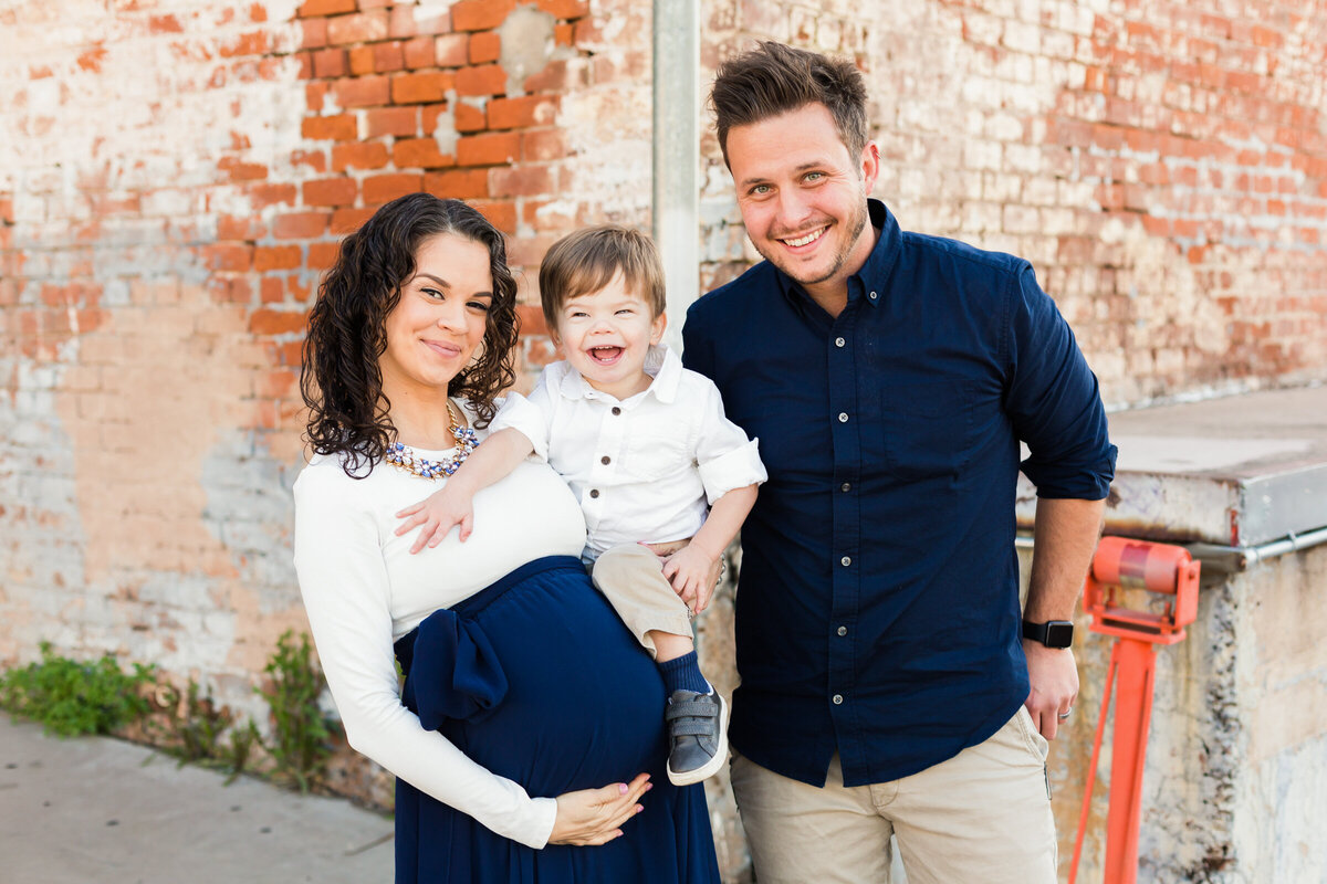 family smiling together and holding baby bump