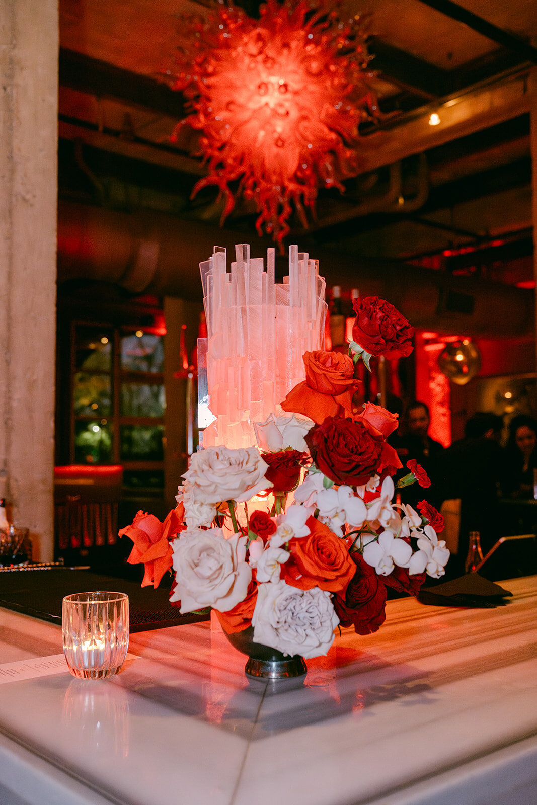Tall florals in modern display beside ice sculpture in industrial wedding bar in San Antonio