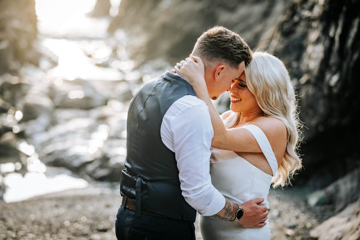 A bride & groom about to kiss on a rocky beach