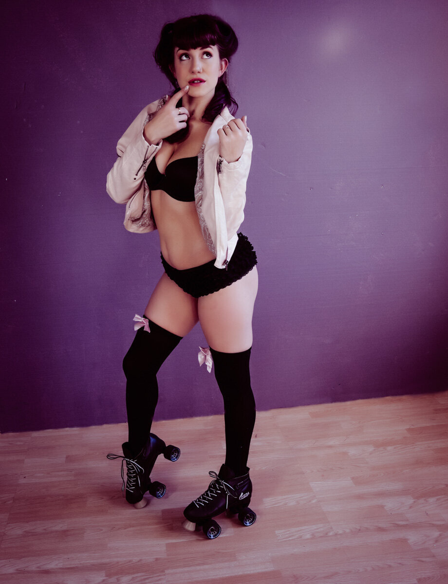 Pinup girl in pink leather jacket and black knee high socks  and roller skates with a purple background  in twin cities