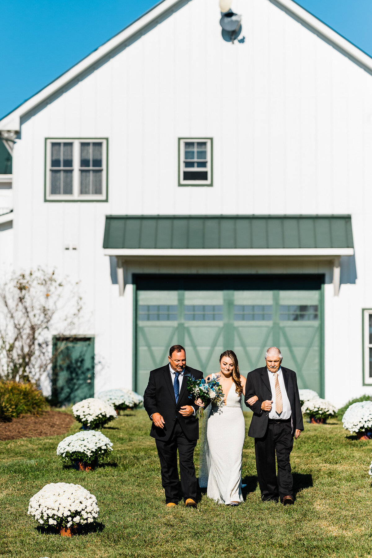 father of the bride and grandfather of the bride walk on either side of the bride as she enters to wedding ceremony captured by Virginia wedding photographer