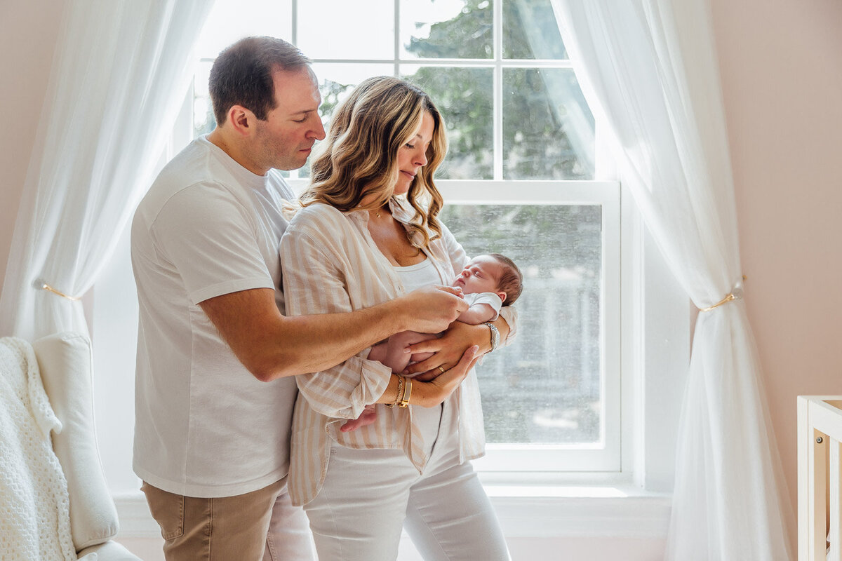 mom and dad by window with baby long  island photographer