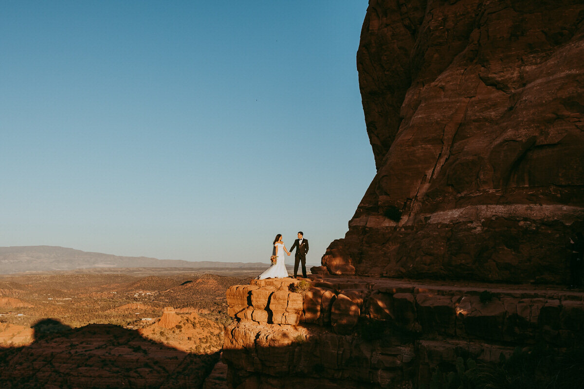 a couple stands on cliff edge of cathedral rock in Sedona