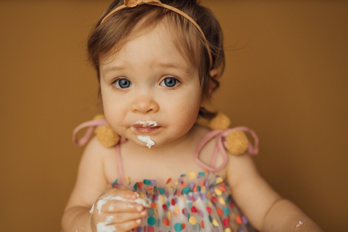 girl looks at camera while eating cake during photo session in land o lakes