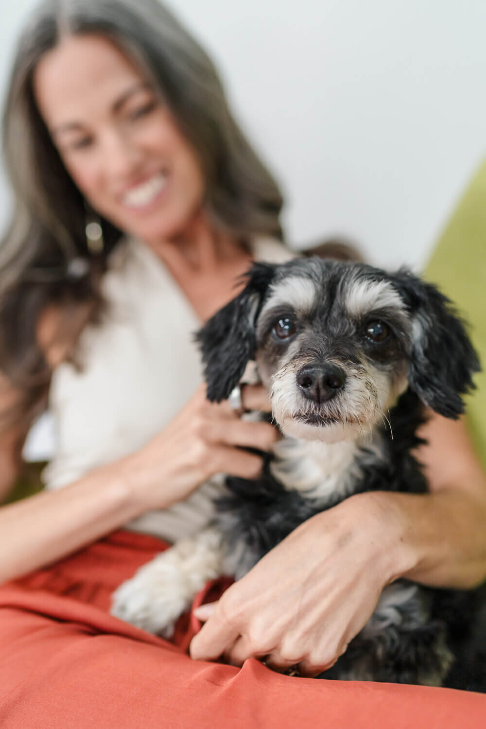 Close-up of black and white dog on Jenn Pike’s lap, with her smiling in background.