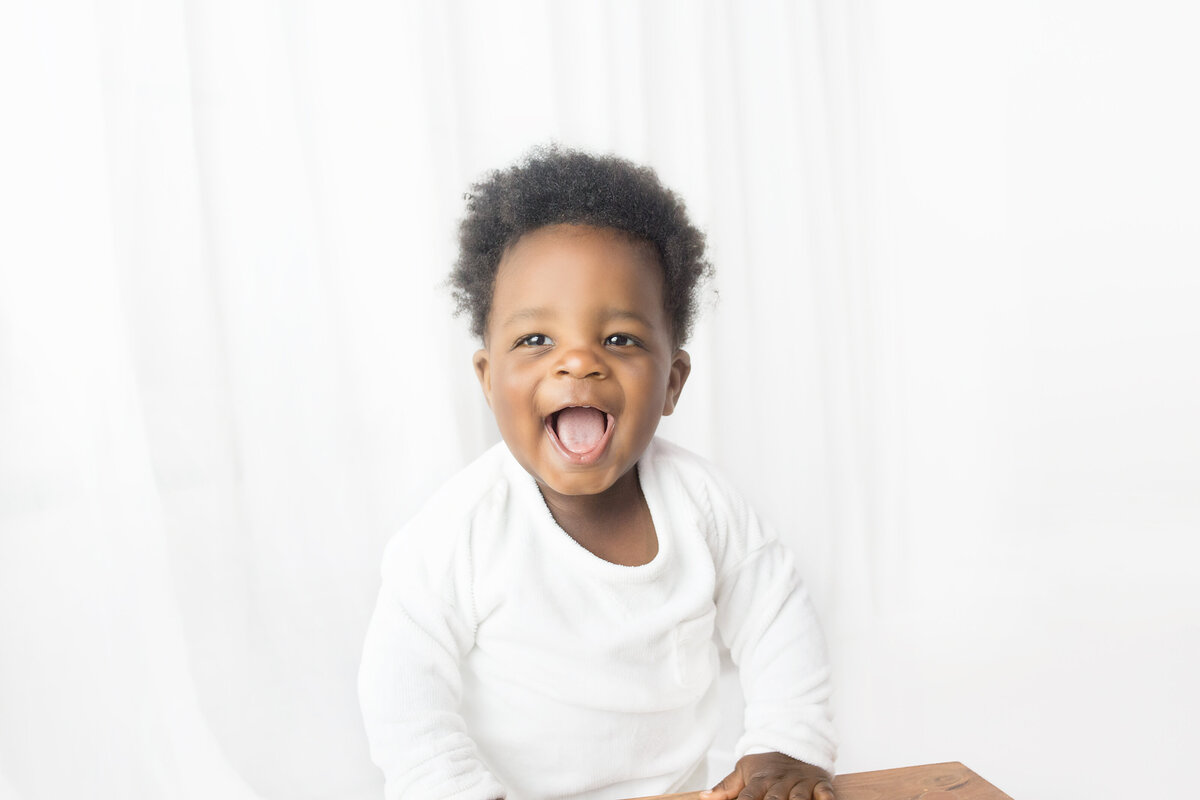 Little boy wearing white during first birthday cake smash photoshoot in Franklin Tennessee photography studio