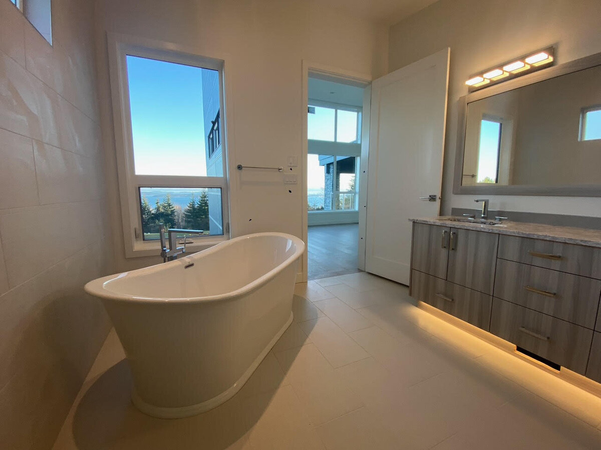 Contemporary ensuite design with freestanding bathtub, tiled flooring, and custom vanity.