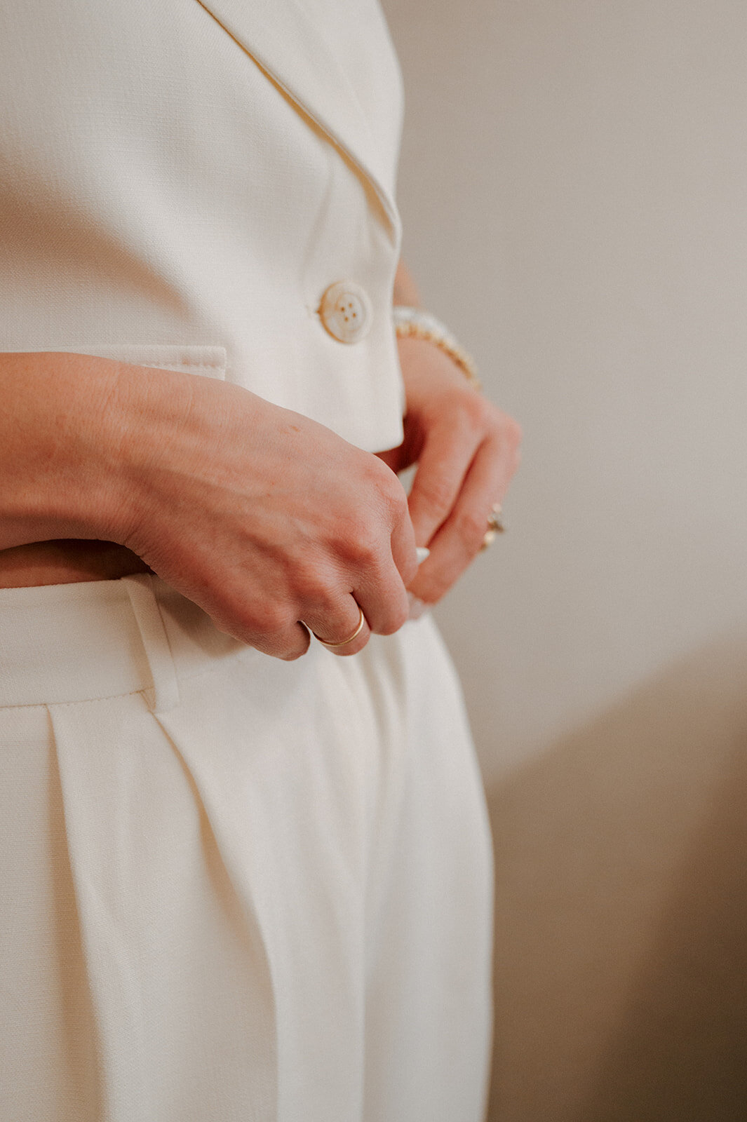 A close up of a woman's hands adjusting the waist of her white pants.