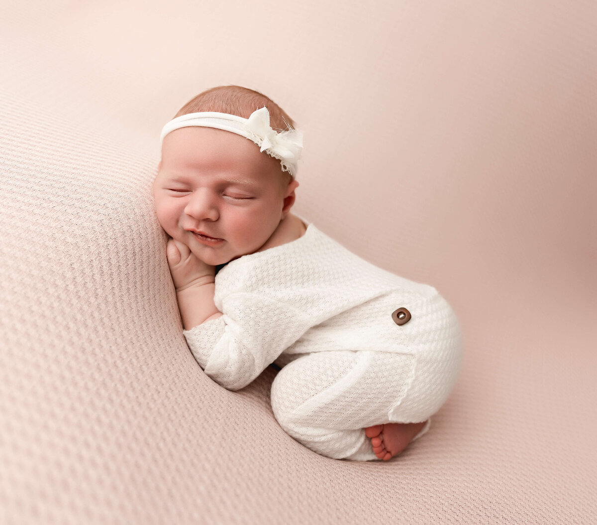 Erie Pa newborn photography studio portrait of a baby girl in a white sleeper in bum up pose