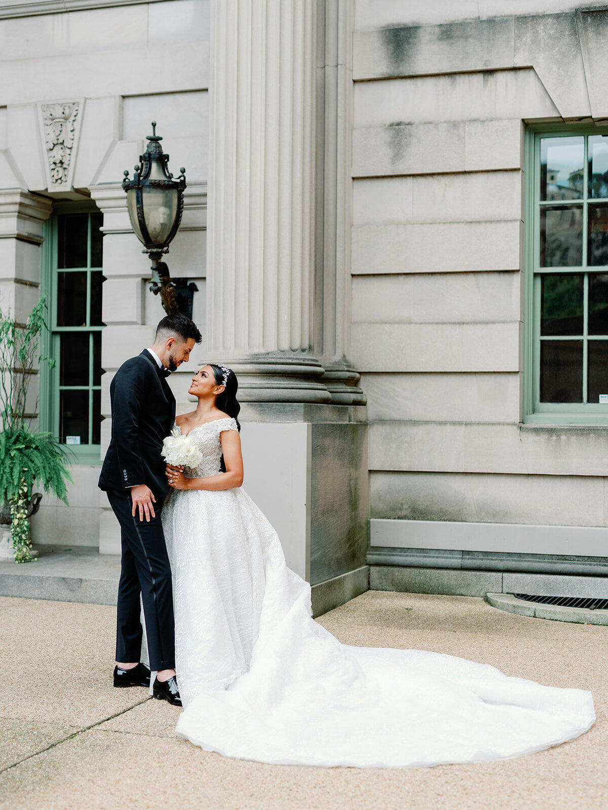 Bride and groom stand in front of Larz Anderson House for portraits.