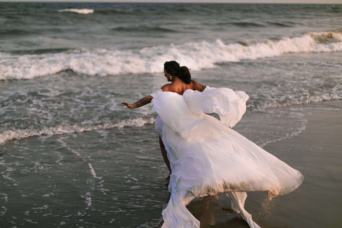 A woman runs into the waves in her wedding dress giving a sense of joy, freedom, and no stress on her wedding day. Captured by Wisconsin wedding photographers O & B Photo Co 