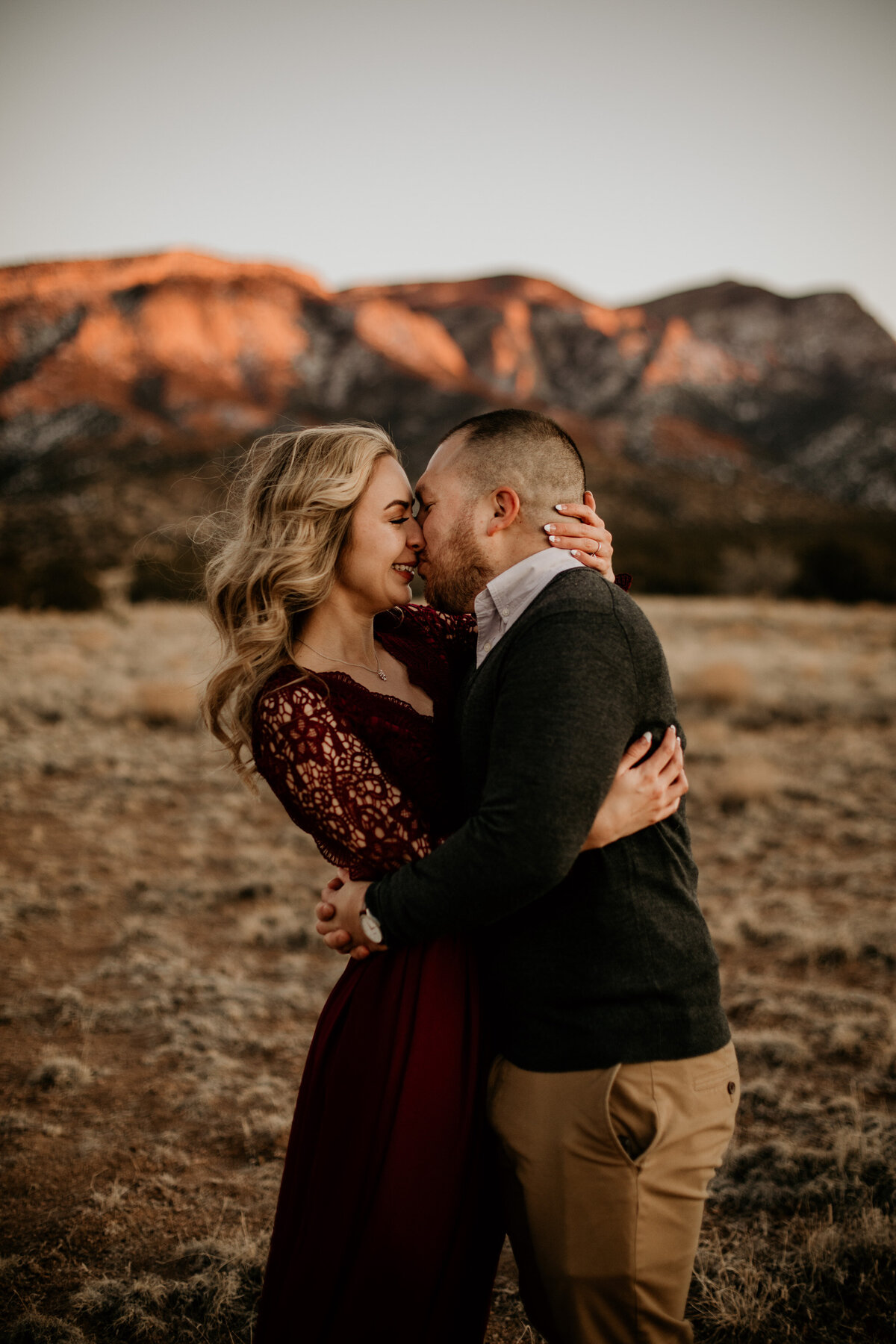 engaged couple kissing with Sandia mountain behind them