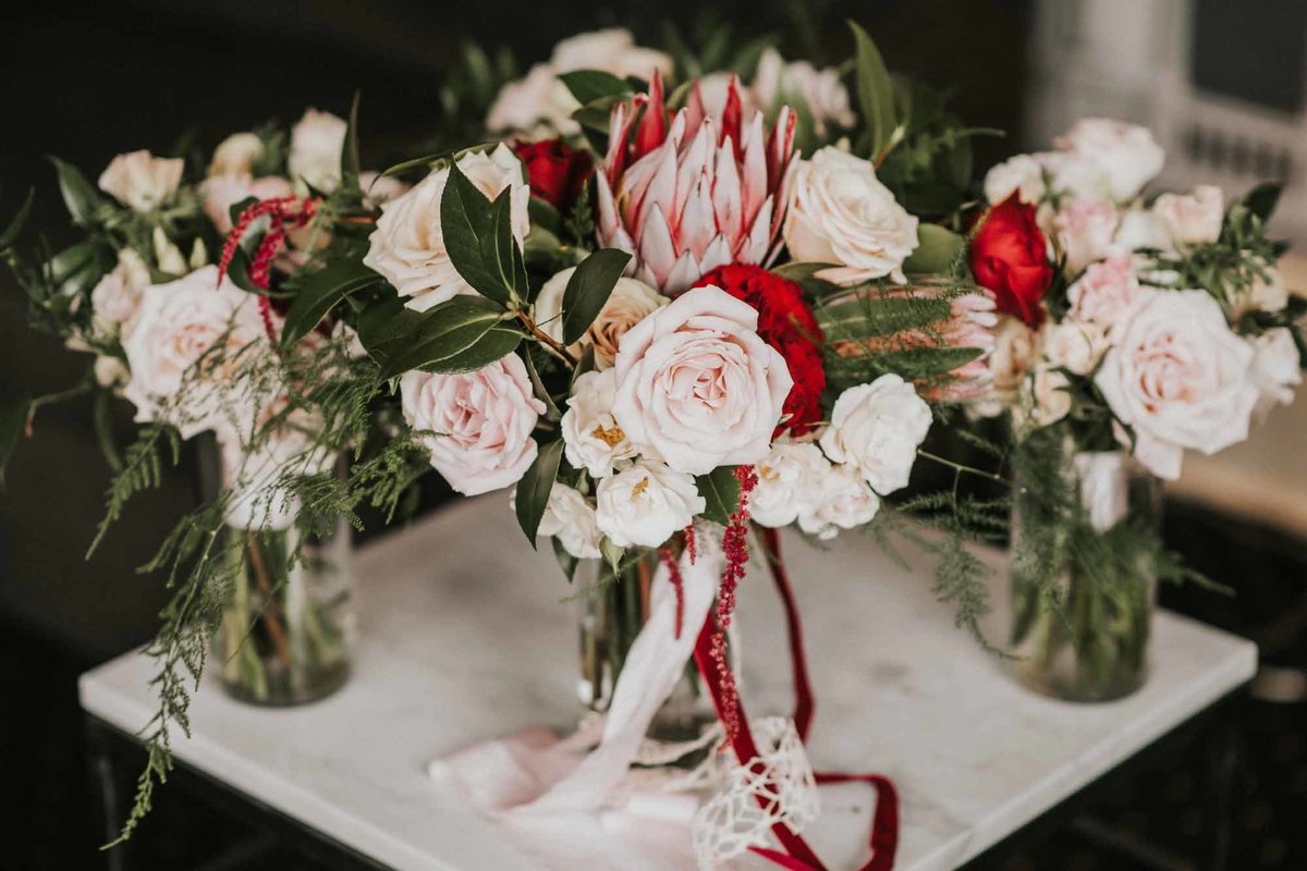 bouquets of red and ivory roses with ribbon streamers for bride's maids