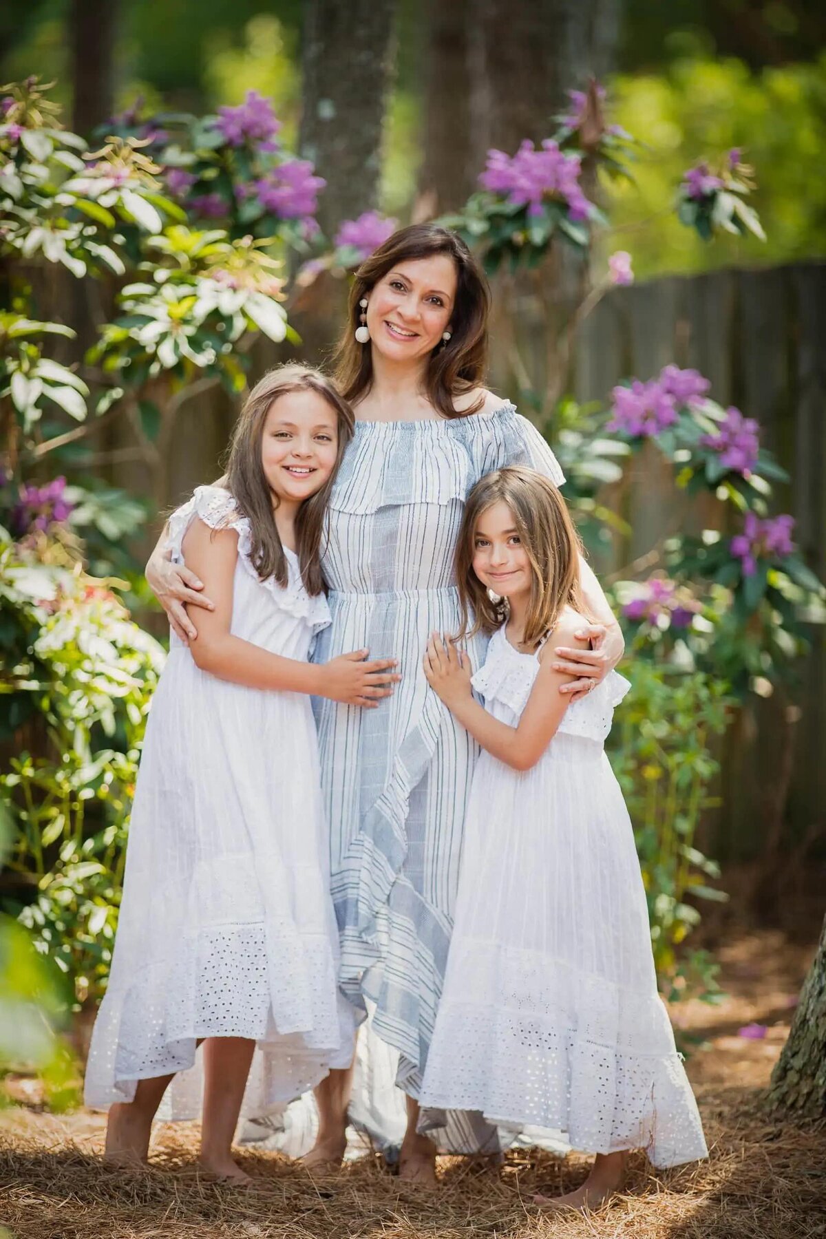 A  mom with her arms around her two daughters.