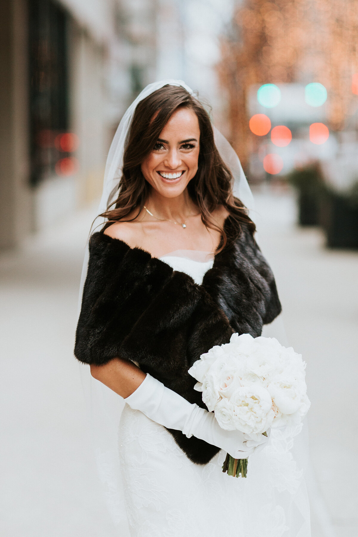 Bride wearing stole and wearing bouquet standing outside