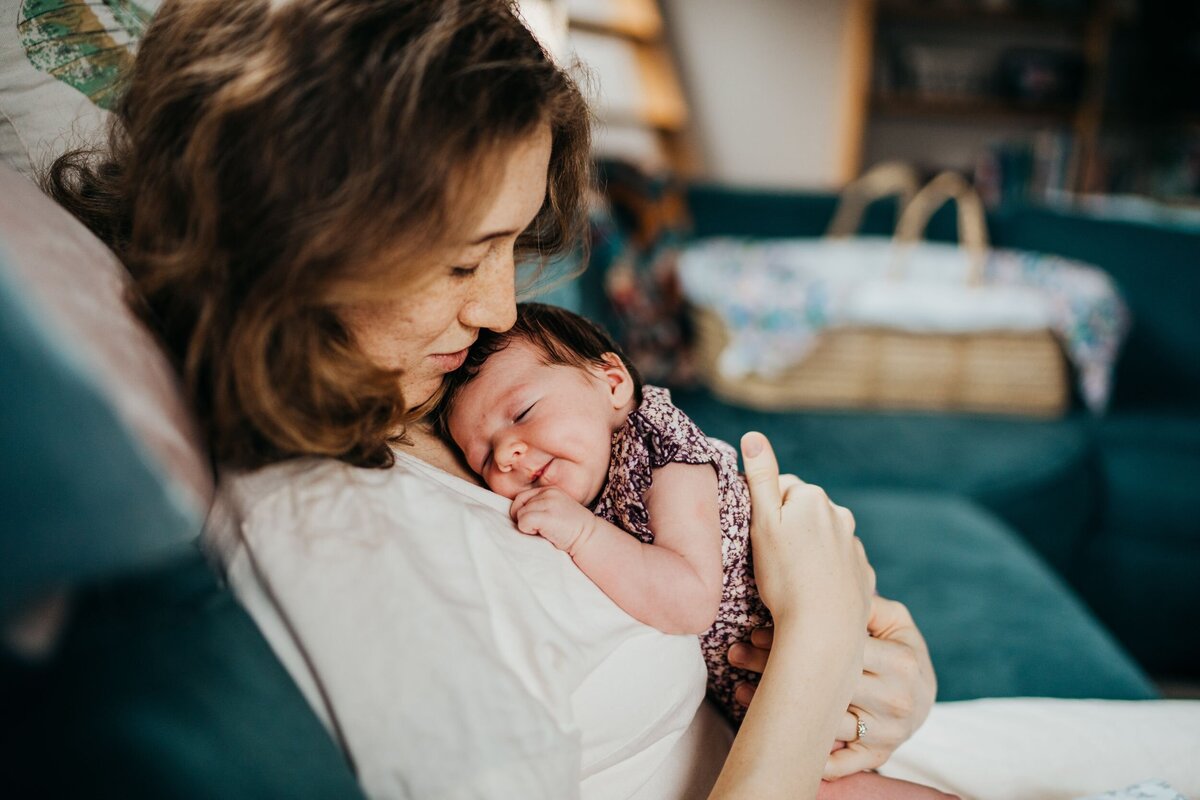 mom-holding-her-newborn-girl-on-her-couch