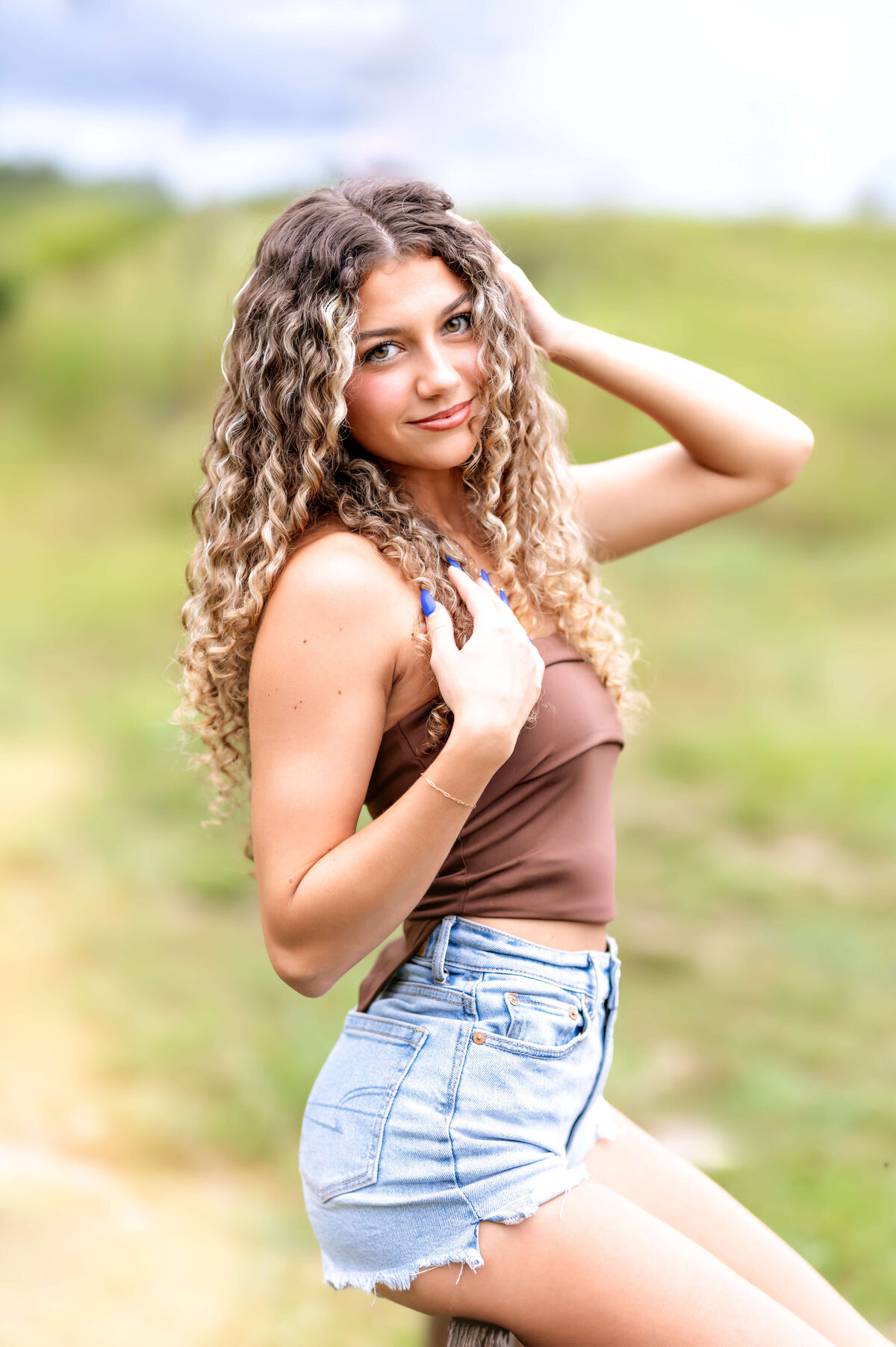 Orlando senior photos featuring a teen girl laughing with her hand in her hair in a golden field.